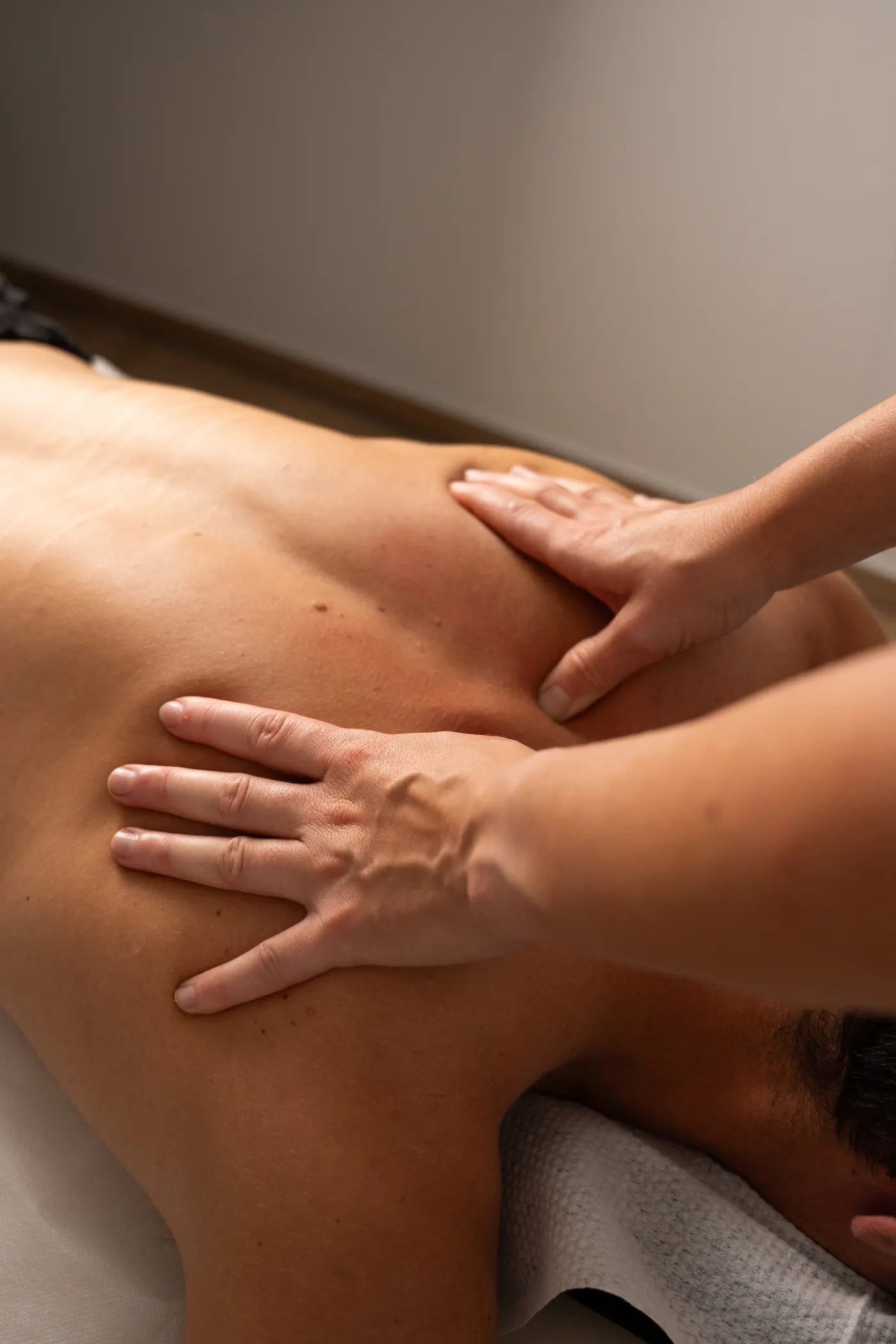 Le mani di un fisioterapista trattano la spalla di un paziente